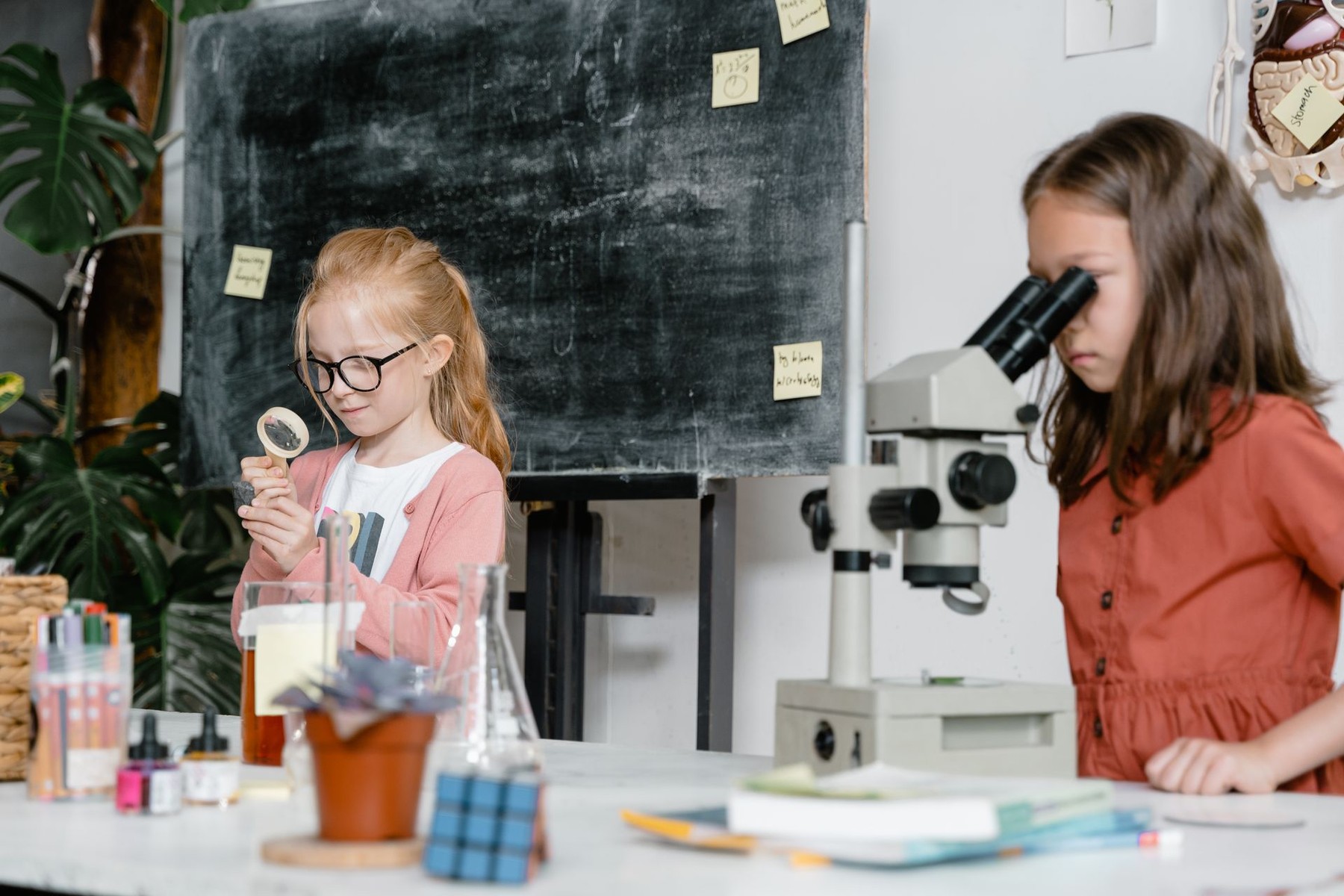Two children exploring science tools in a classroom learning environment